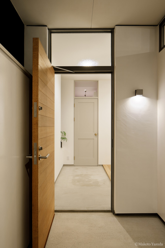 Источник вдохновения для домашнего уюта: входная дверь среднего размера в стиле модернизм с белыми стенами, бетонным полом, одностворчатой входной дверью, входной дверью из светлого дерева и серым полом