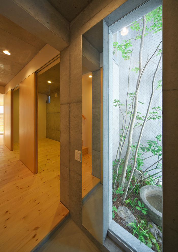 Réalisation d'une entrée minimaliste de taille moyenne avec un couloir, un mur blanc, parquet clair, une porte coulissante et un sol marron.