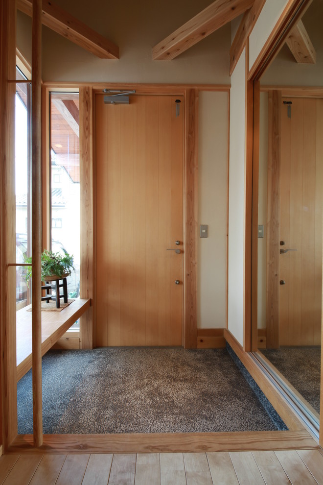 Cette photo montre une entrée asiatique avec un mur beige, une porte en bois clair, un sol gris et une porte simple.