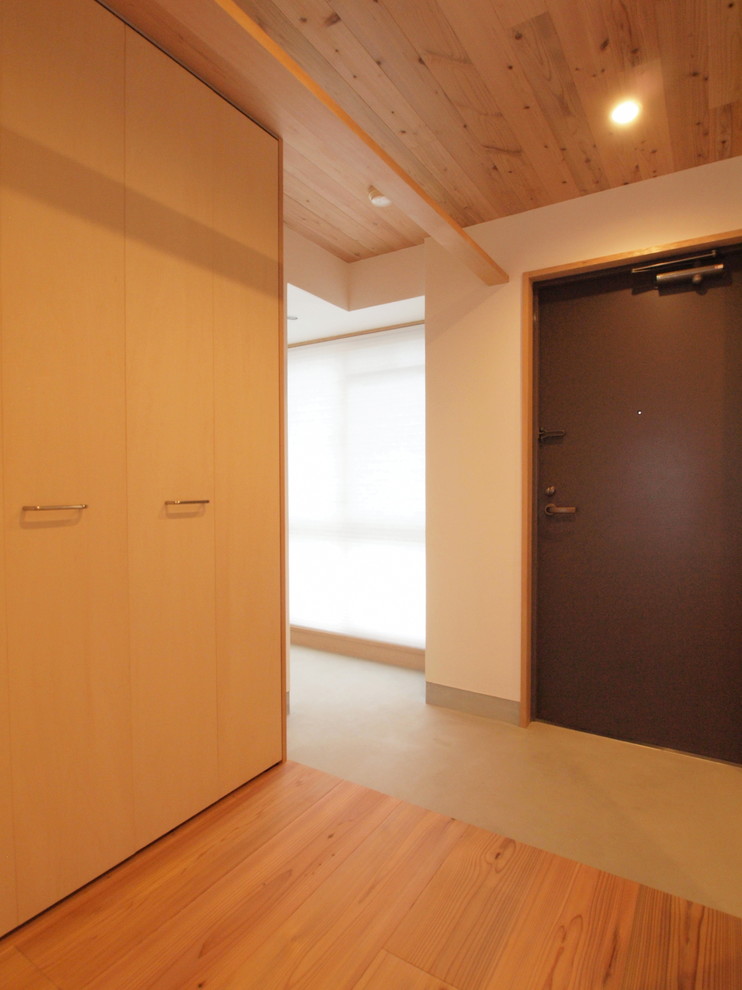 Exemple d'une entrée scandinave avec un couloir, un mur blanc, un sol en bois brun et un sol marron.