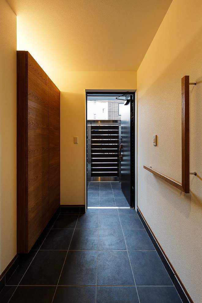 Inspiration pour une grande entrée minimaliste avec un couloir, un mur blanc, un sol en carrelage de porcelaine, une porte simple, une porte noire et un sol noir.