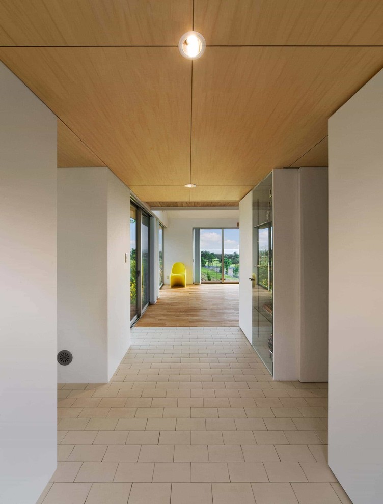 Inspiration pour une entrée nordique avec un couloir, un mur blanc, un sol en brique, une porte simple, un sol blanc et une porte en bois brun.