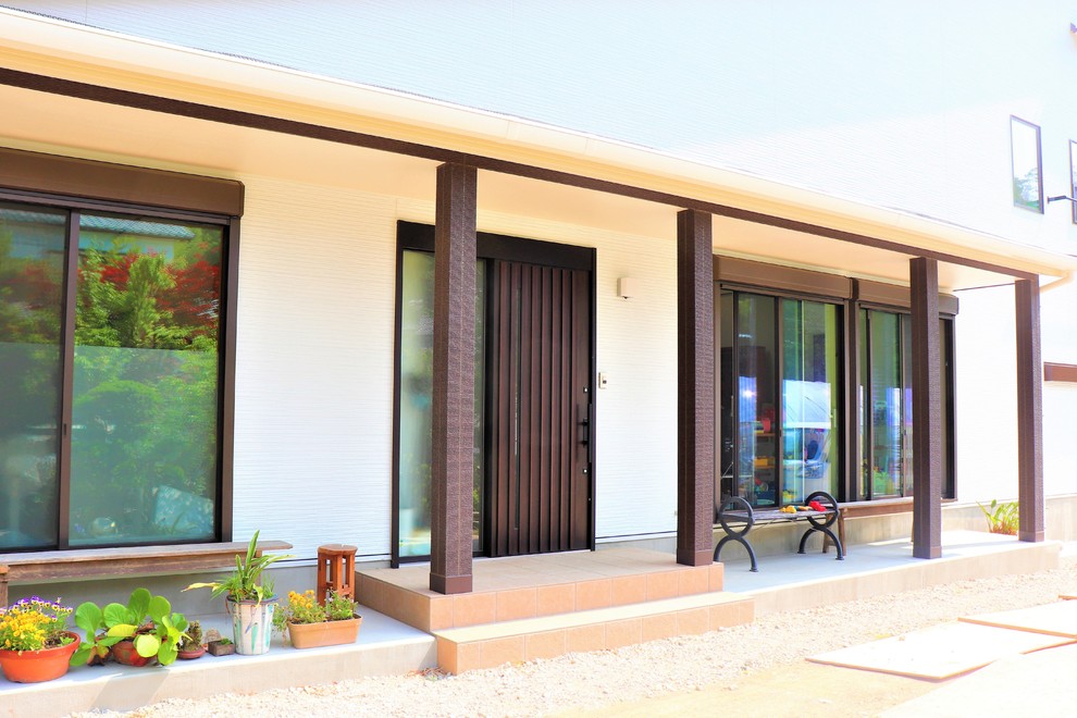 Cette image montre une entrée design avec un mur blanc, une porte coulissante et une porte marron.