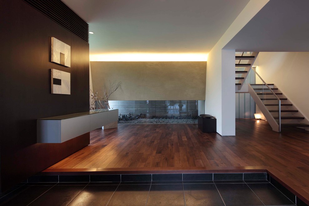 Inspiration pour une entrée minimaliste avec un mur blanc, parquet foncé, une porte en bois foncé et un sol marron.