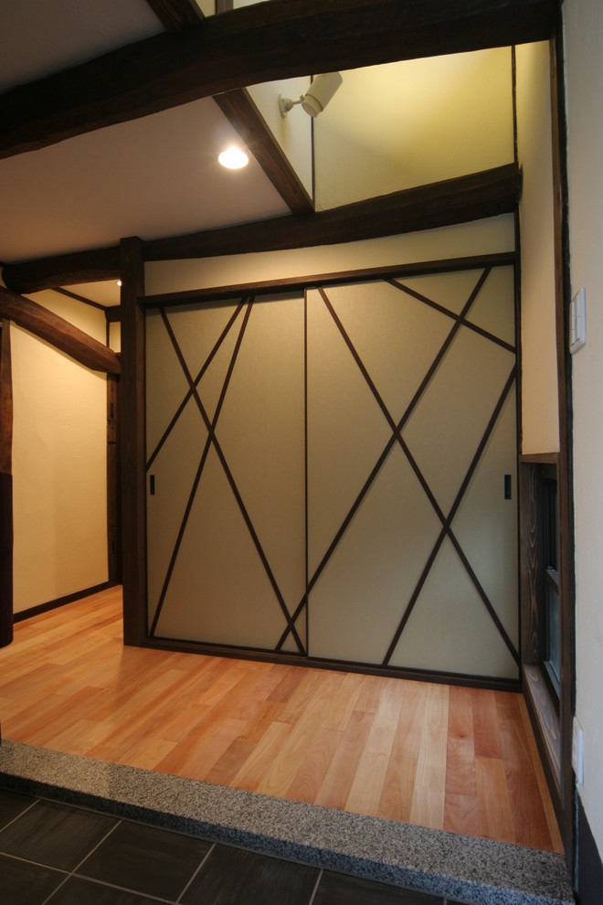 Exempel på en asiatisk hall, med vita väggar, mellanmörkt trägolv, en skjutdörr, mörk trädörr och brunt golv