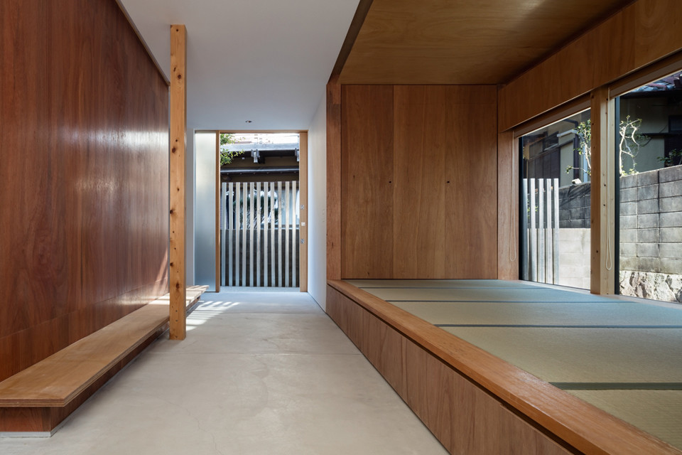 Diseño de hall de estilo zen de tamaño medio con paredes marrones, suelo de cemento, puerta corredera, puerta de madera clara y suelo gris