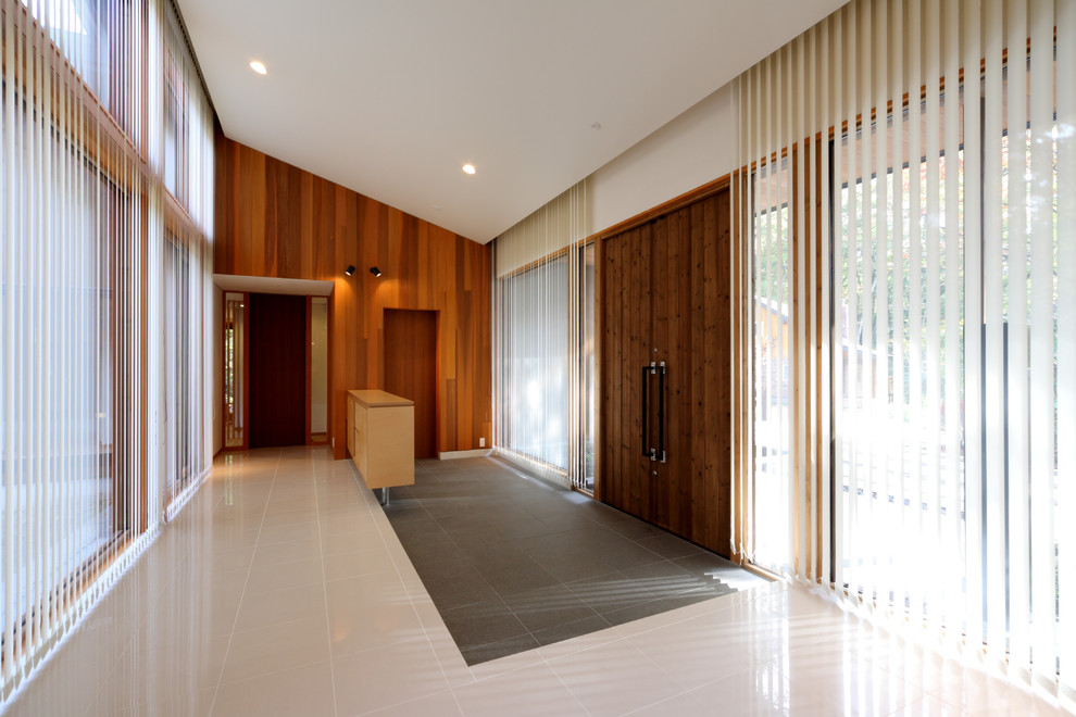 他の地域にある広いモダンスタイルのおしゃれな玄関ホール (白い壁、磁器タイルの床、茶色いドア、白い床) の写真