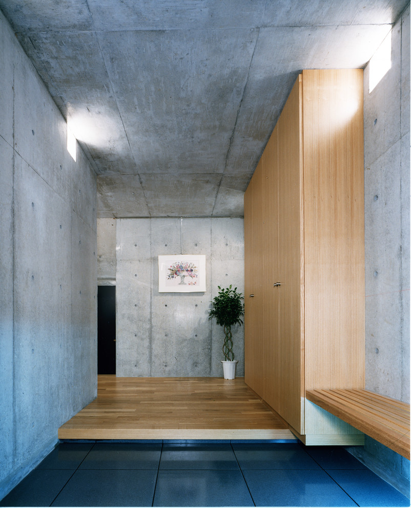 Ispirazione per un grande corridoio industriale con pareti grigie, pavimento con piastrelle in ceramica, una porta singola, una porta in legno bruno e pavimento grigio