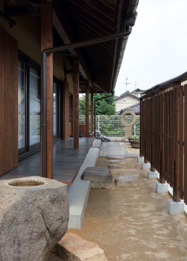 Réalisation d'un porche d'entrée de maison asiatique avec une extension de toiture.