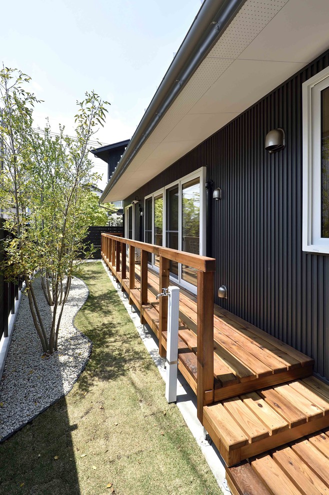Réalisation d'un grand porche avec un jardin potager arrière asiatique avec une terrasse en bois et une extension de toiture.
