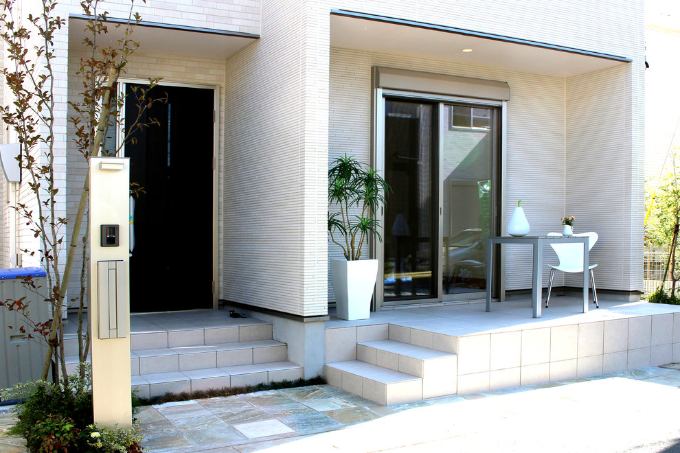 Bild på en funkis veranda längs med huset, med kakelplattor
