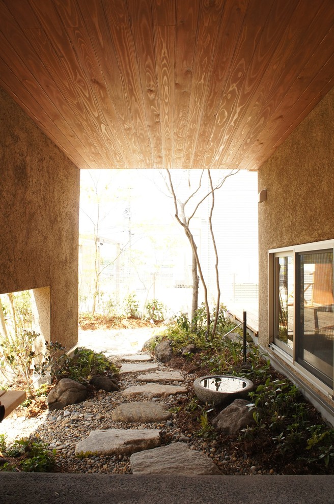 Ispirazione per un portico minimalista davanti casa con pavimentazioni in pietra naturale e un tetto a sbalzo