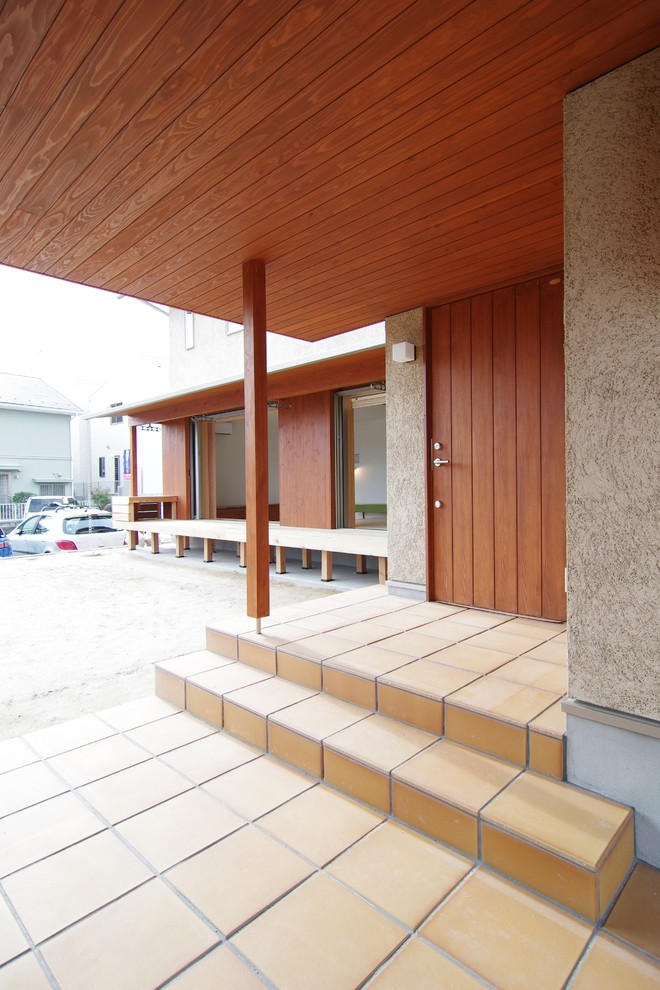 Esempio di un portico minimalista davanti casa con pavimentazioni in mattoni e un tetto a sbalzo