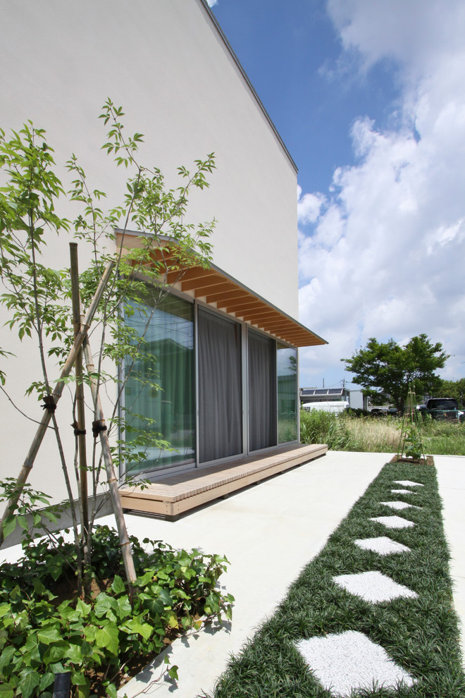 Réalisation d'un porche d'entrée de maison avant asiatique avec une terrasse en bois.