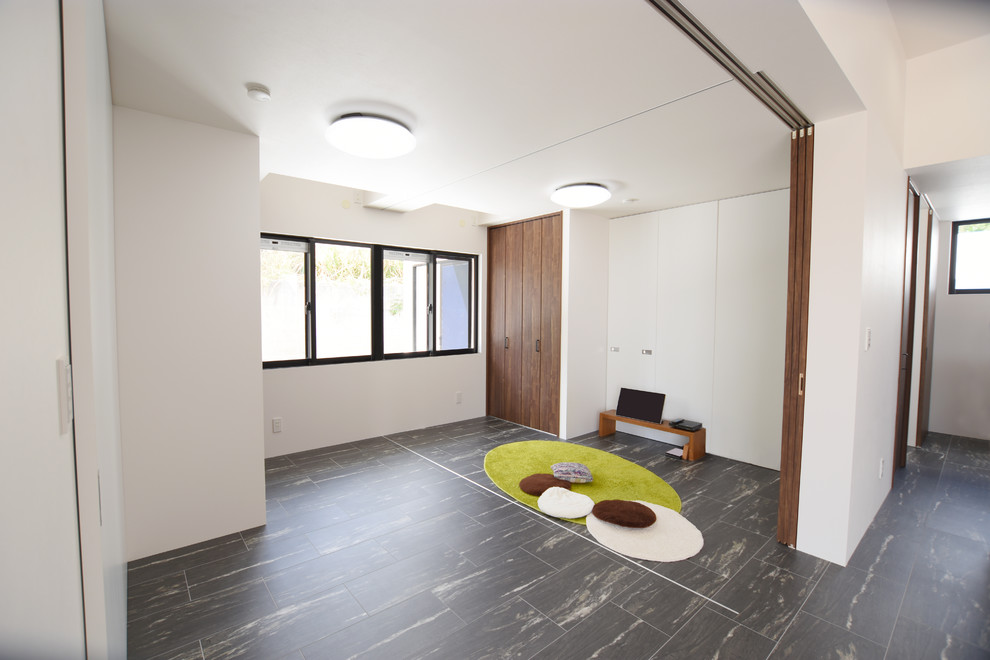 Foto di una cameretta per neonati neutra minimalista con pareti bianche, pavimento in vinile e pavimento nero