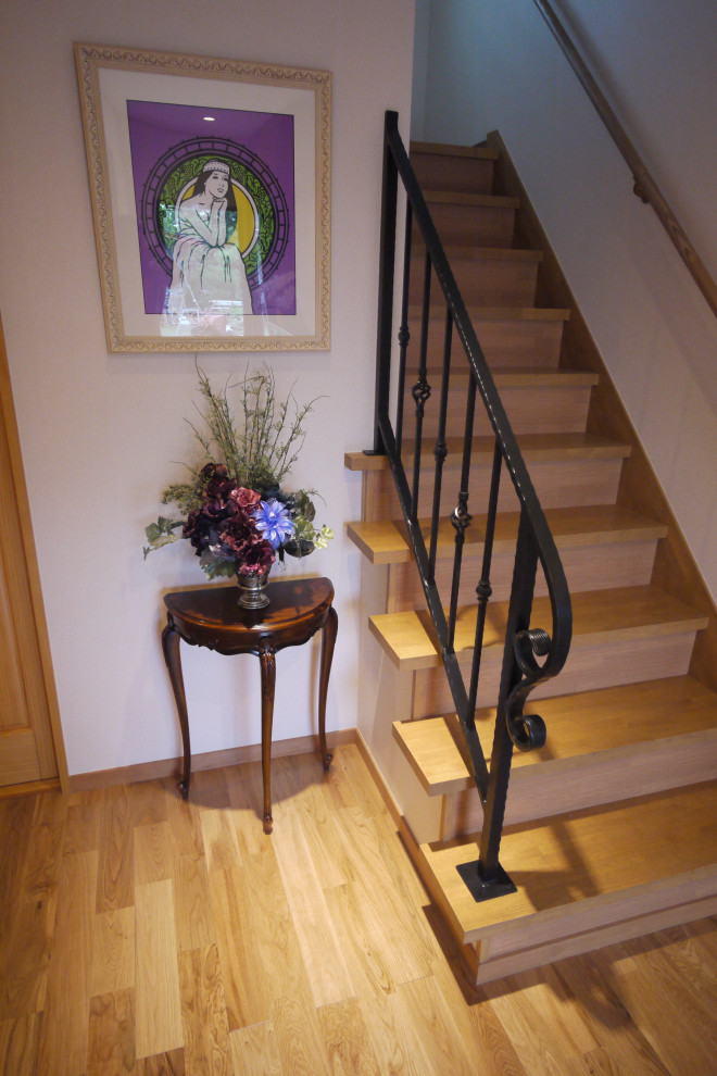 Cette image montre un escalier peint traditionnel en U de taille moyenne avec des marches en bois peint, un garde-corps en métal et du papier peint.