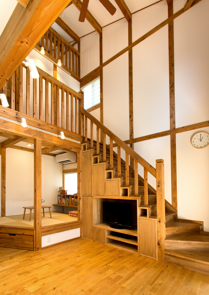 Exemple d'un escalier asiatique en L avec des marches en bois, des contremarches en bois, un garde-corps en bois et un téléviseur en dessous.