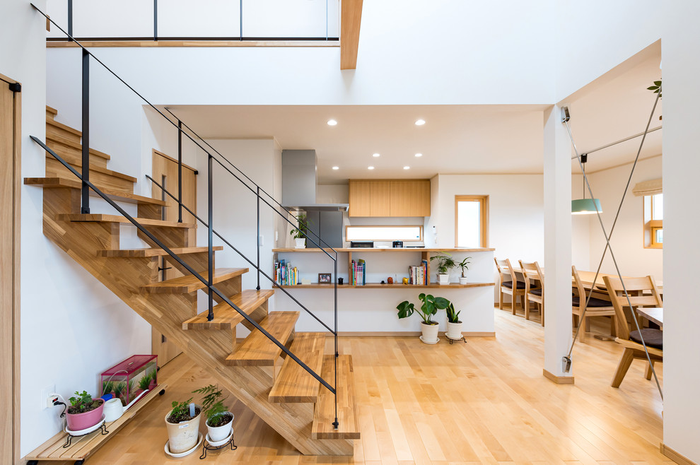 Cette photo montre un escalier droit tendance avec des marches en bois, des contremarches en bois, un garde-corps en métal et du papier peint.