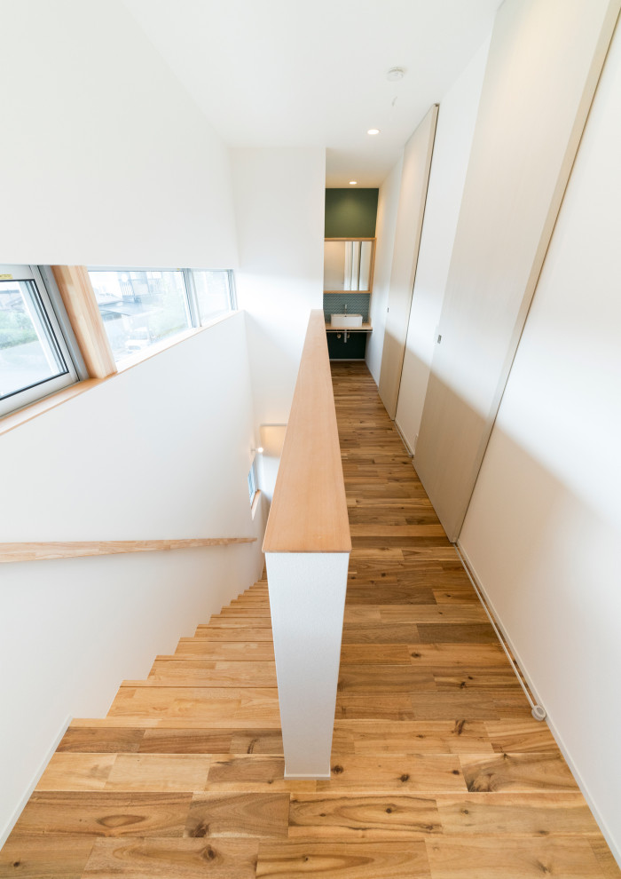 Foto de escalera recta nórdica pequeña con escalones de madera, contrahuellas de madera, barandilla de madera y papel pintado