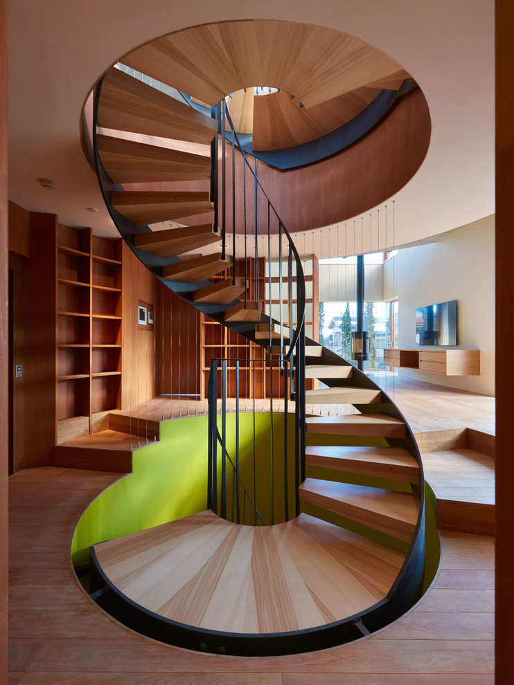 Идея дизайна: винтовая лестница в современном стиле с деревянными ступенями и металлическими перилами без подступенок