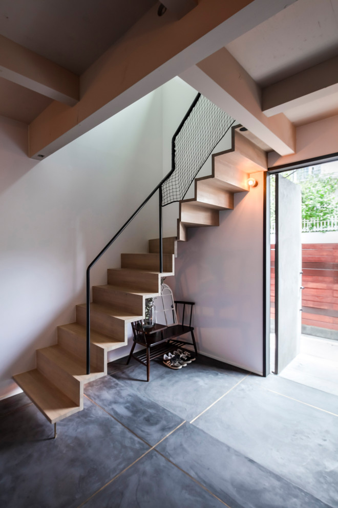 Exemple d'un escalier sans contremarche courbe tendance avec des marches en bois, un garde-corps en métal et éclairage.