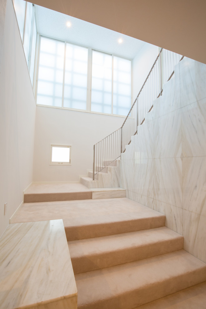 На фото: огромная п-образная лестница в стиле модернизм с ступенями с ковровым покрытием, ковровыми подступенками, металлическими перилами и деревянными стенами с