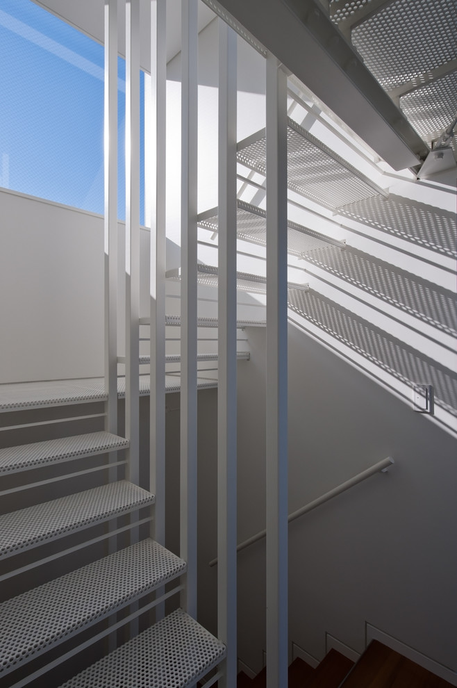 На фото: п-образная лестница в современном стиле с металлическими ступенями и металлическими перилами с