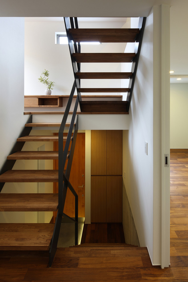 Foto de escalera en U asiática sin contrahuella con escalones de madera y barandilla de metal