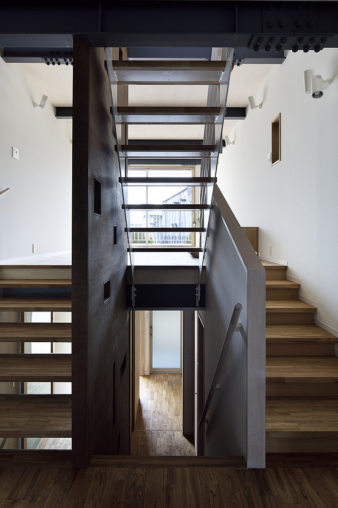 Идея дизайна: большая изогнутая лестница в современном стиле с деревянными ступенями и металлическими перилами