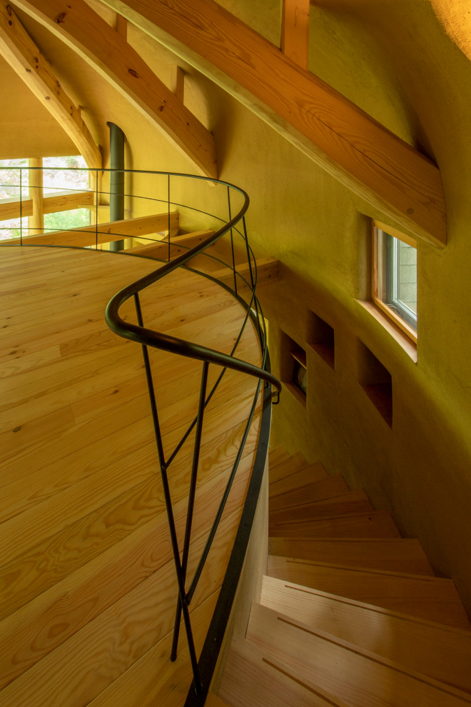 他の地域にある高級な小さなコンテンポラリースタイルのおしゃれなサーキュラー階段 (木の蹴込み板、金属の手すり) の写真