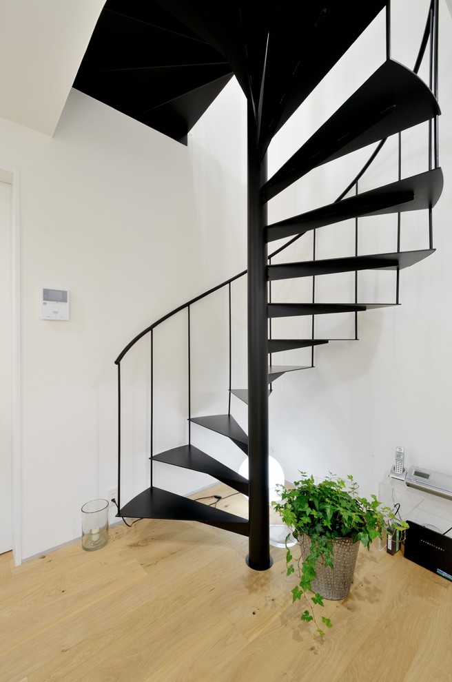 Cette image montre un escalier sans contremarche hélicoïdal minimaliste avec des marches en métal et un garde-corps en métal.