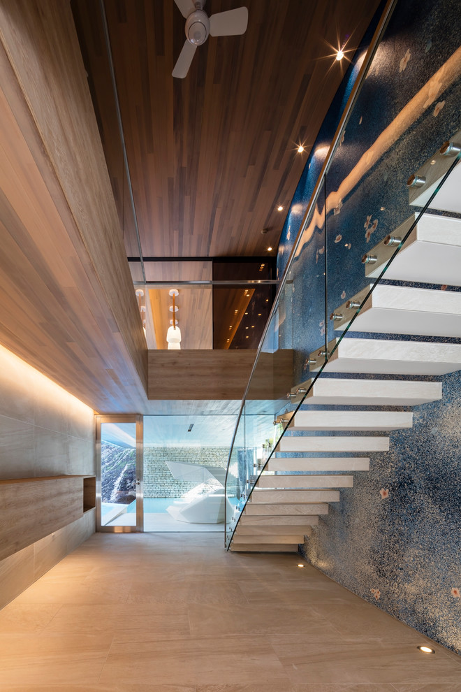Aménagement d'un escalier sans contremarche droit contemporain en béton avec un garde-corps en verre.