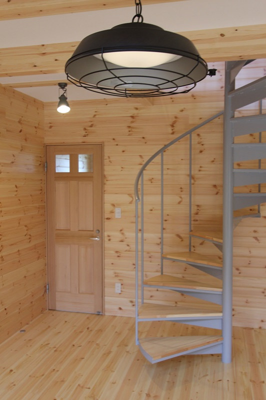 На фото: большая винтовая лестница в стиле лофт с деревянными ступенями, металлическими перилами и панелями на стенах без подступенок с