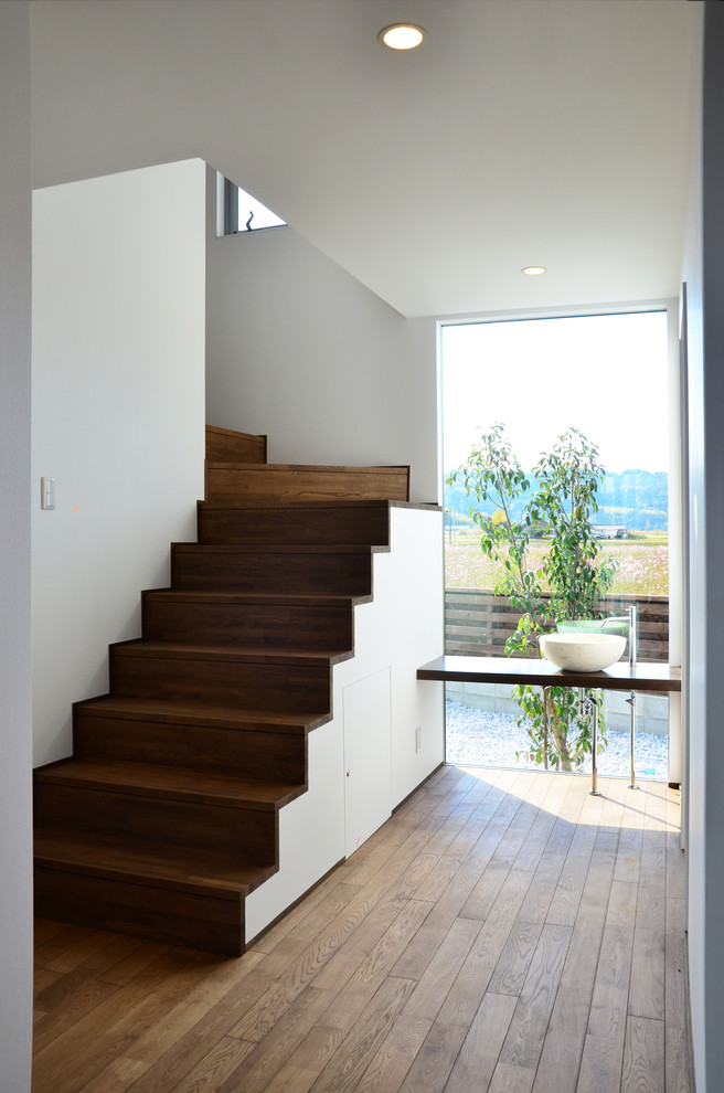 Cette image montre un petit escalier minimaliste en U avec des marches en bois, des contremarches en bois et éclairage.