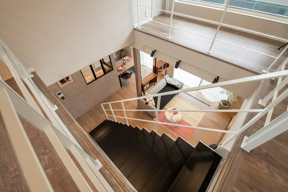Ejemplo de escalera recta minimalista de tamaño medio sin contrahuella con escalones de madera, barandilla de metal y panelado
