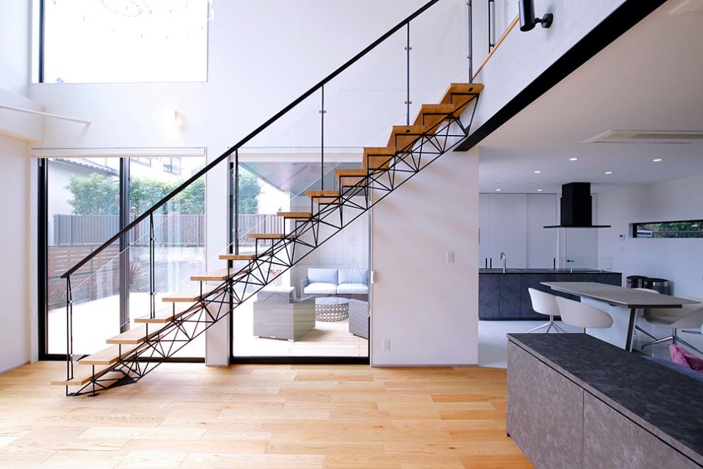 Aménagement d'un grand escalier sans contremarche droit industriel avec des marches en bois, un garde-corps en verre et du papier peint.
