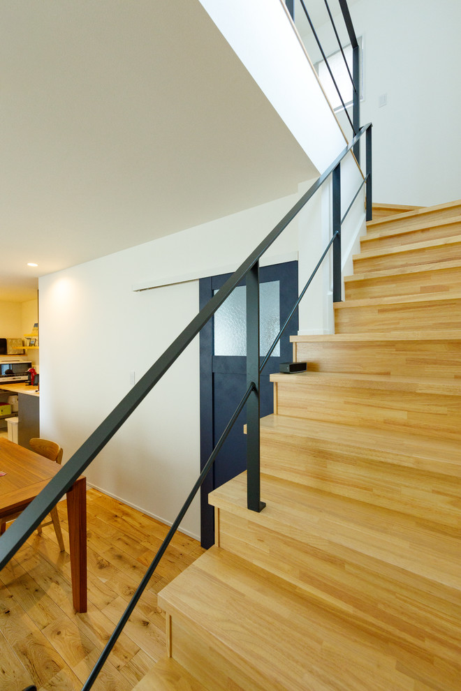 Ejemplo de escalera recta nórdica de tamaño medio con escalones de madera, contrahuellas de madera, barandilla de metal y papel pintado