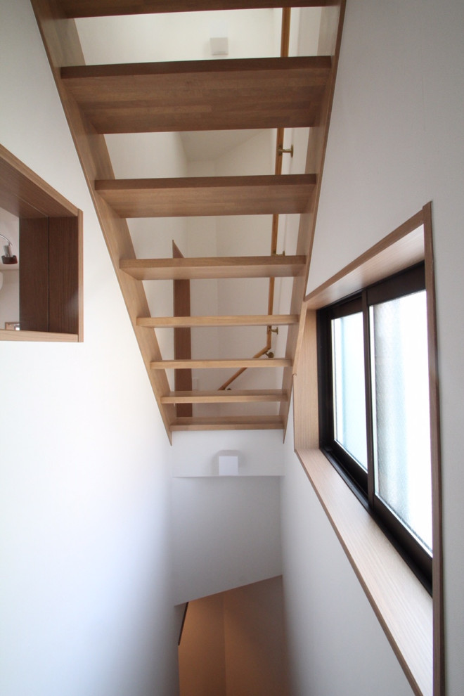 Foto de escalera recta nórdica pequeña con escalones de madera, contrahuellas de madera, barandilla de madera y papel pintado