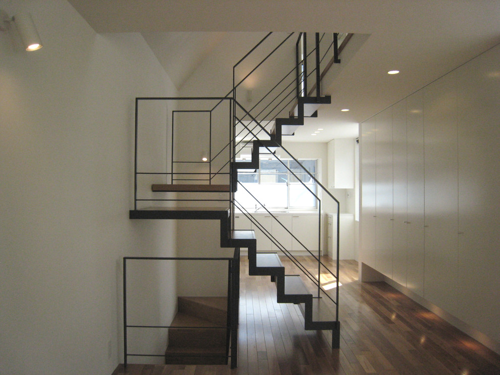 Réalisation d'un petit escalier sans contremarche minimaliste en U avec des marches en bois et un garde-corps en métal.