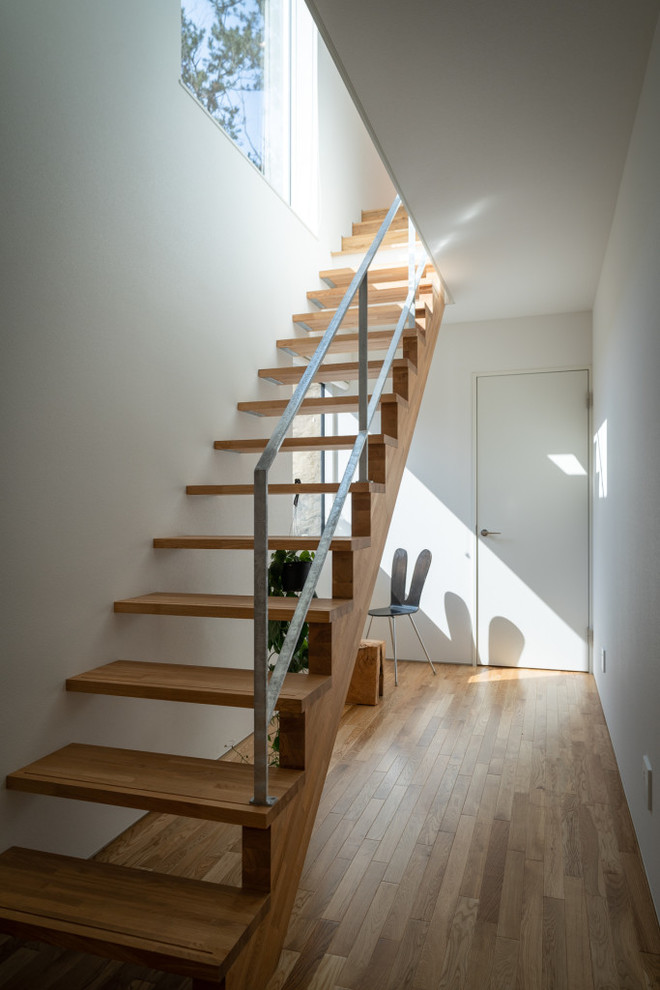Cette photo montre un escalier sans contremarche droit scandinave avec des marches en bois et un garde-corps en métal.