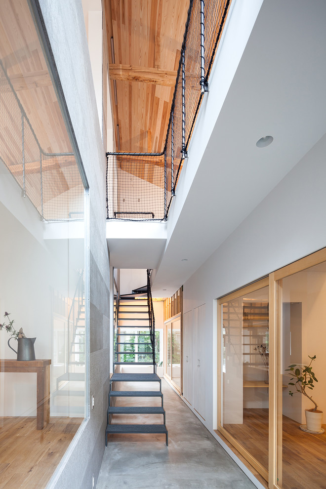 На фото: изогнутая лестница в стиле модернизм с металлическими перилами без подступенок
