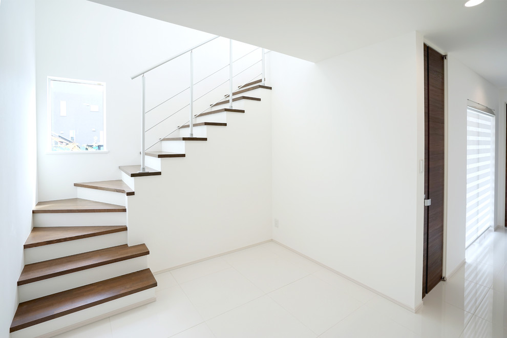 Ejemplo de escalera en L minimalista grande con escalones de madera, contrahuellas de madera, barandilla de metal y papel pintado