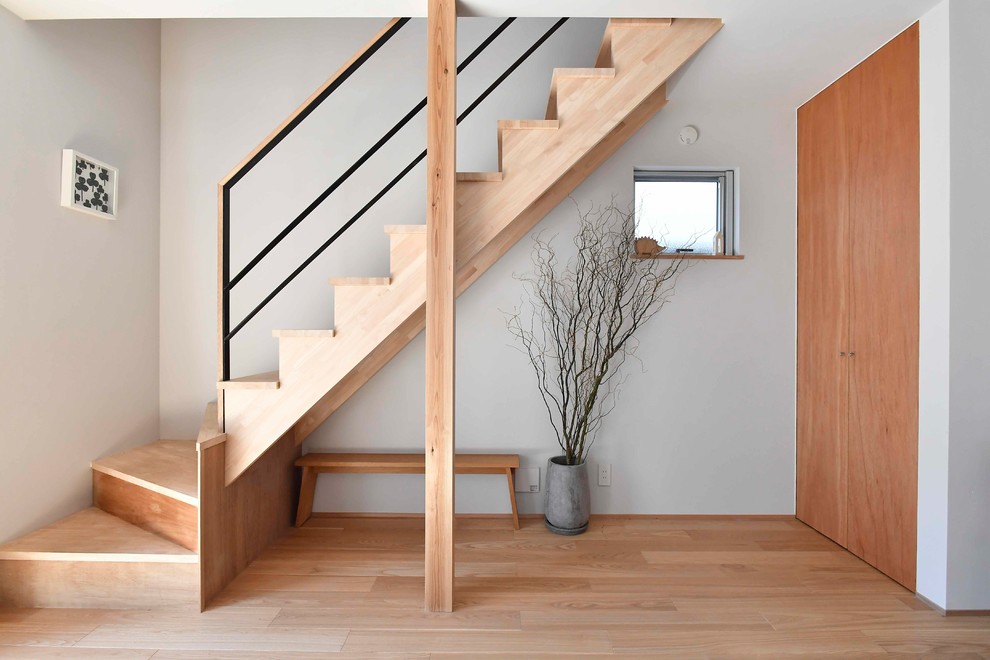 На фото: прямая деревянная лестница в скандинавском стиле с деревянными ступенями и перилами из смешанных материалов