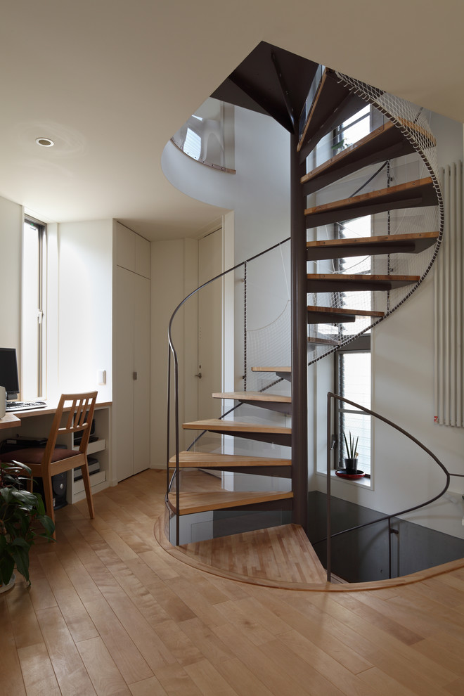 Inspiration pour un escalier sans contremarche hélicoïdal design avec des marches en bois, un garde-corps en métal et éclairage.