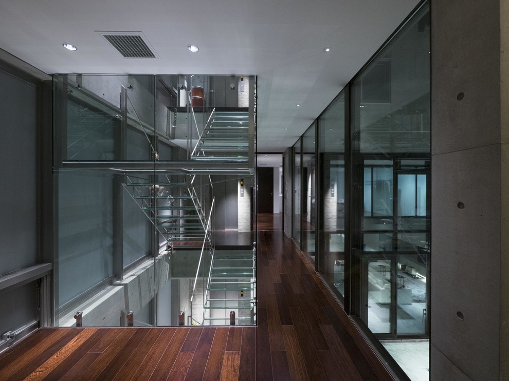 На фото: п-образная лестница в стиле лофт с стеклянными ступенями и металлическими перилами без подступенок