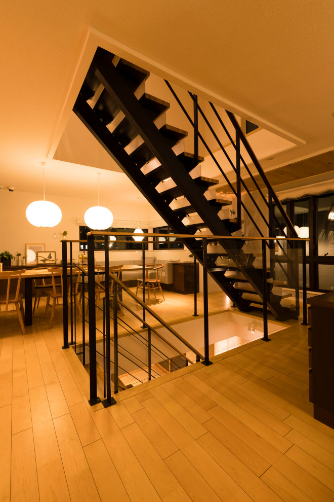 Cette photo montre un escalier droit moderne de taille moyenne avec des marches en bois, des contremarches en verre et un garde-corps en métal.