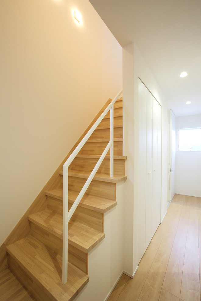 Imagen de escalera recta actual con escalones de madera, contrahuellas de madera y barandilla de metal