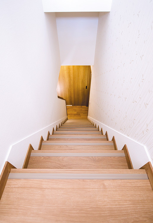 他の地域にある小さなコンテンポラリースタイルのおしゃれな直階段 (木の蹴込み板、壁紙) の写真