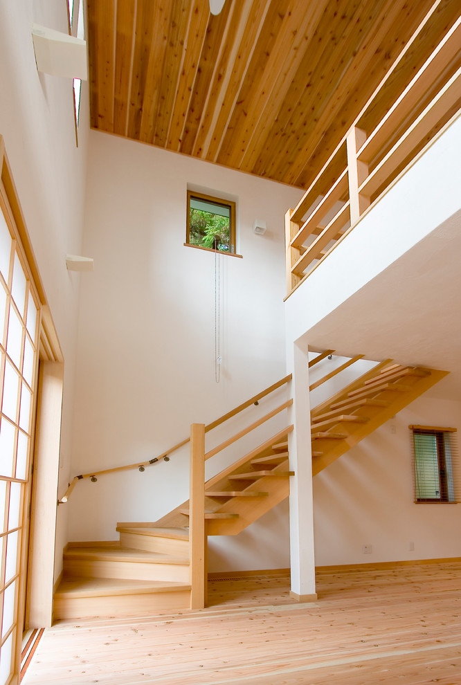 Стильный дизайн: изогнутая лестница в восточном стиле с деревянными ступенями и деревянными перилами без подступенок - последний тренд