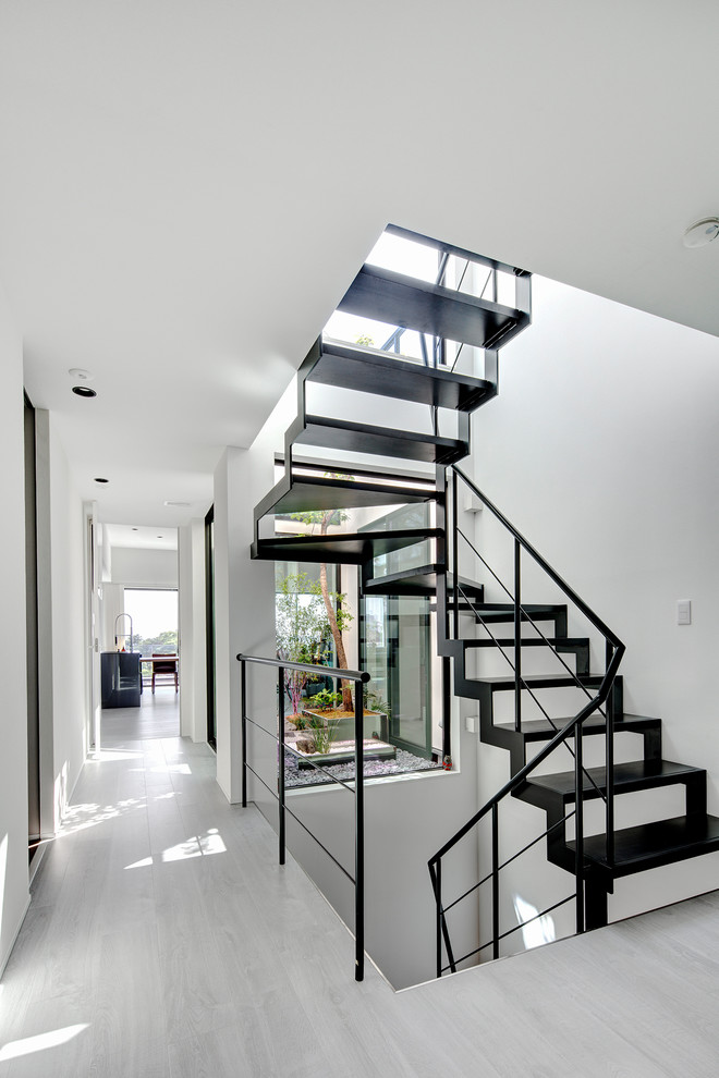 Modern u-shaped metal railing staircase in Tokyo with open risers.
